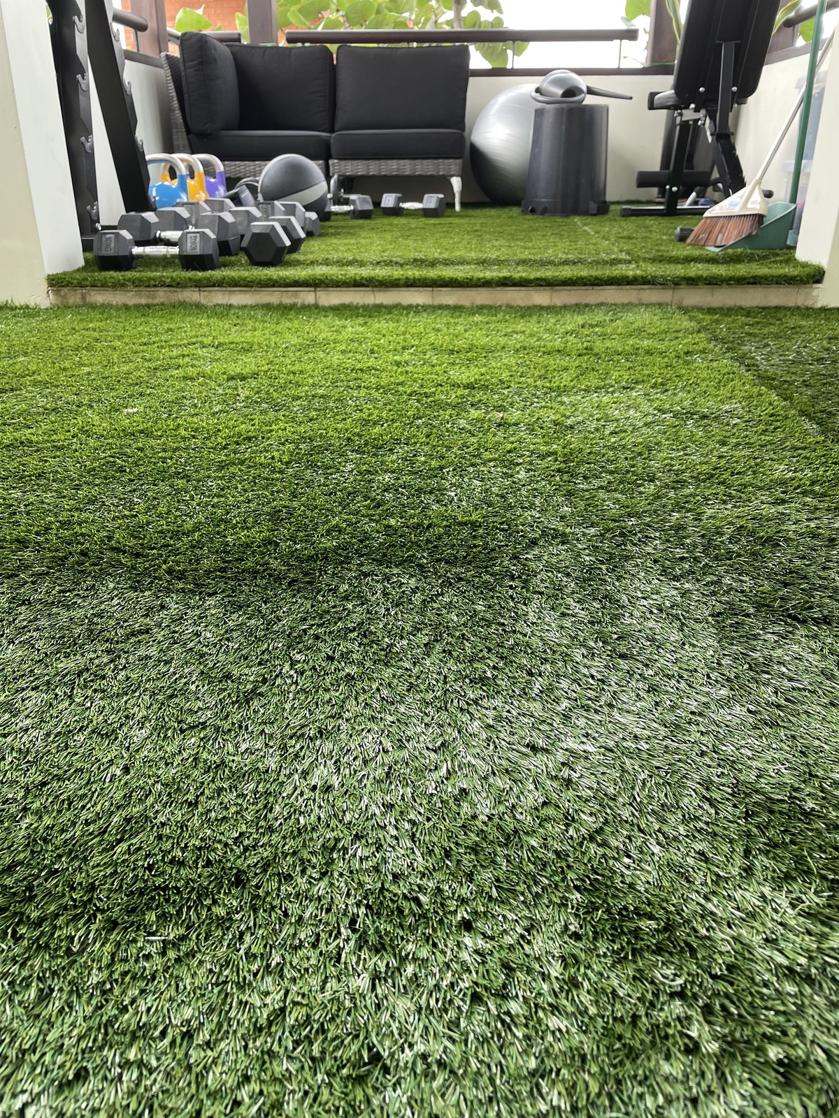 Sheltered home gym with artificial grass flooring and dumbbells