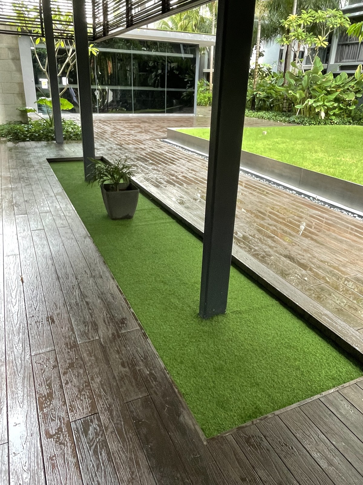 Landscaped walkway strip with artificial grass beside a commercial deck