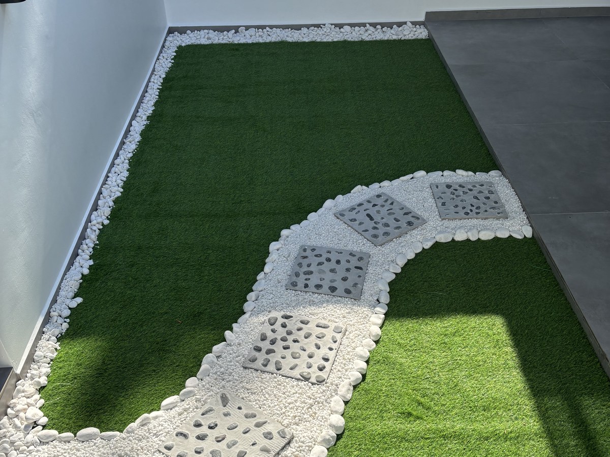 Landed home side yard with artificial grass and a pebble stepping-stone path