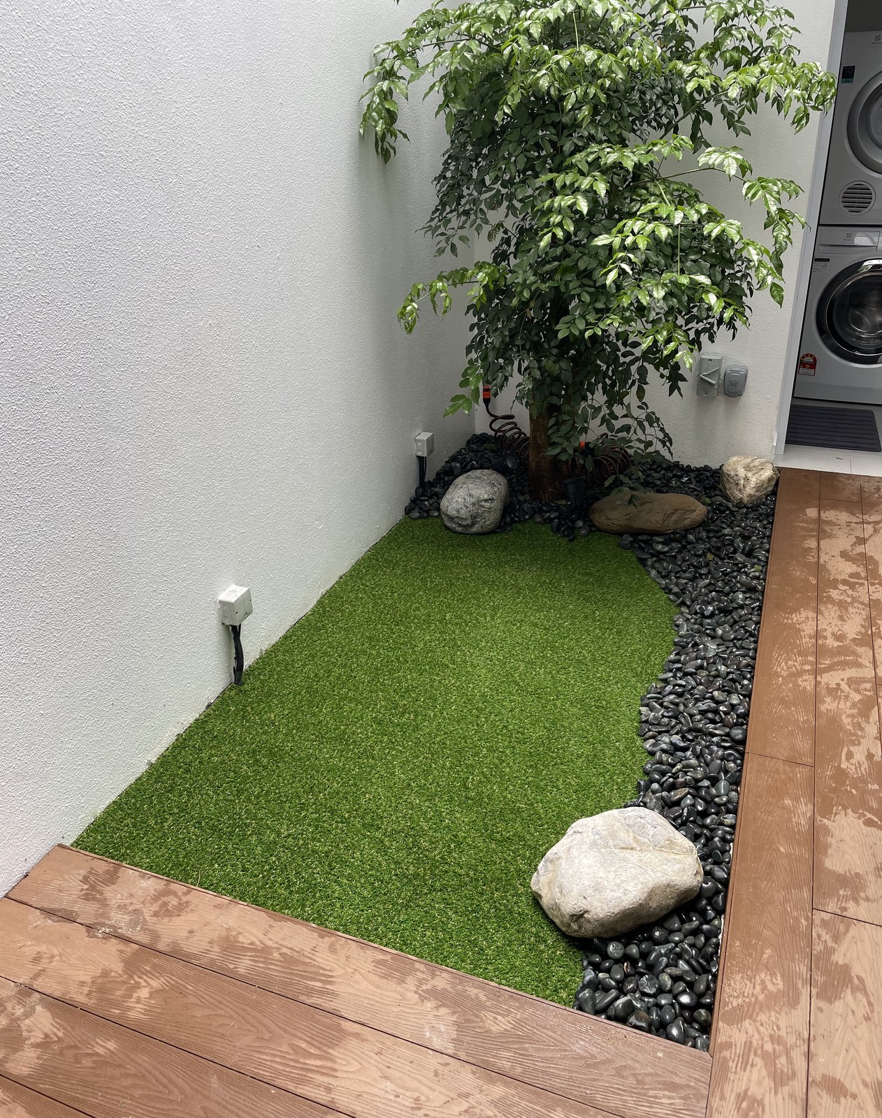 Airwell courtyard with artificial grass, potted plants and stones