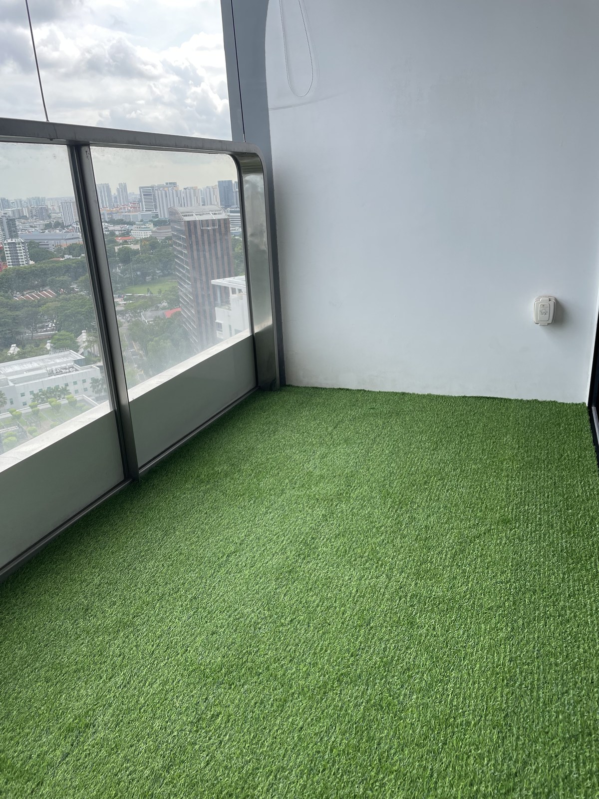 Condo balcony with artificial grass and lounge chairs overlooking a pool